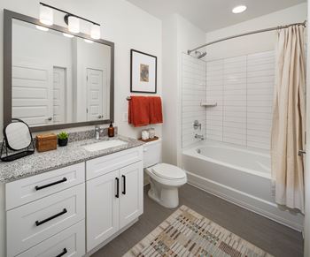 A bathroom with a white toilet, sink, and a shower with a beige shower curtain.